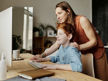 A parent helping a child use a computer at home